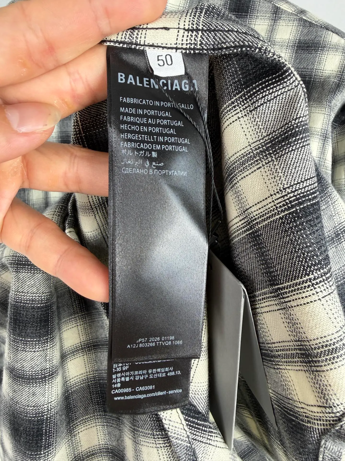 BALENCIAGA/balenciaga Black White plaid pocket embroidered logo shirt jacket The technical difficulties of this plaid shirt focus on fabric finishing, plaid matching and component sewing details. The fabric has been sanded and distressed to create a fine velvet feel on the surface, changing the original luster of the fabric and making the Black and White plaid colors transition softly. At the same time, the drape properties of the fabric itself are retained, taking into account the looseness of the upper body and the silhouette of the body, without appearing soft and shapeless. The biggest test of plaid garments comes from the alignment of the pieces. The front and rear body, large and small sleeves, and chest pockets are all independent pieces. In the cutting stage, the horizontal and vertical axes of the plaid need to be aligned, and the external chest bag is cut separately. The plaid on the bag surface needs to form a visual coordination with the main body of the garment. Cutting and typesetting will produce additional fabric loss, and there are high requirements for the cutting accuracy of the cutting bed typesetting and workers. The collar adopts a double-layer combined structure, and the collar surface and collar seat are double-stitched with even and regular stitching spacing to ensure the lapel's long-lasting shape and resistance to warping and deformation after repeated bending. The placket is sewn with regular topstitching and paired with Black matte buttons. The button points need to be aligned with the checkered lines to avoid damaging the overall visual order. The splicing of the cuffs also takes into account the grain direction, and the overlocking process reinforces the seams to improve the durability of the garment. After the entire garment is sewn, it also undergoes a garment washing process to further strengthen the Retro texture of the fabric, unify the tone and texture of the entire garment, weaken the harshness of industrial production, and finally present a relaxed Retro garment effect. Size: 46 48 50 52